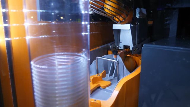 Orange juice vending machine cutting device in progress, fruits fall down and split on two pieces.