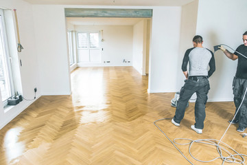Einölen von Eichenparkett, Arbeiter mit poliermaschine und Werkzeug.