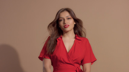 woman in red dress on beige background looking to the camera, dating look