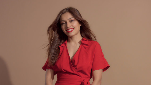 woman in red dress on beige background smiling to the camera, dating look