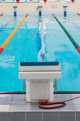 Pedestal For Swimmers In The Indoor Pool With Blue Water And Colored Dividers Of Swimming Track