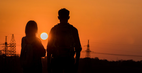 Two teenagers look forward to the sunset of a large sun over the city