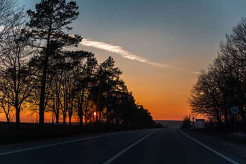 Landscape of unreal natural sunset on road from inside of car.