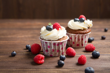 Homemade cupcakes with berries on a wooden background
