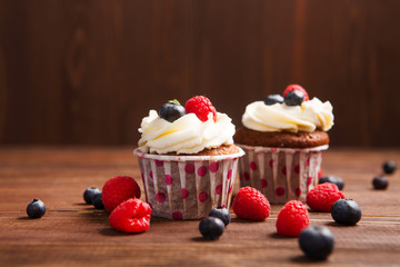 Homemade cupcakes with berries on a wooden background