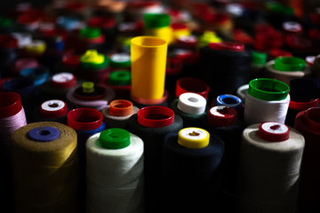 Dark background of colored thread coils for sewing