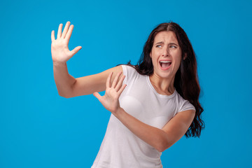 Studio portrait of a young beautiful woman in a white t-shirt against a blue wall background. People sincere emotions.