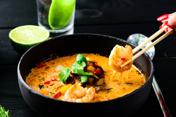 Spicy seafood noodles on black wood background.
