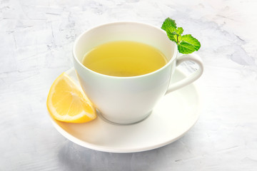 A cup of tea with a slice of lemon and mint leaves, with copy space