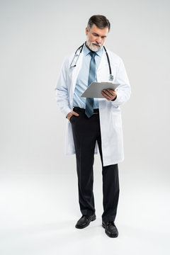 Full Body Picture Of A Mature Doctor Holding A Notepad, On White Background.