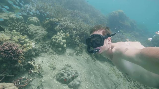 Diver is swimming snorkeling and making underwater selfie video in ocean. Tropical vacation concept.