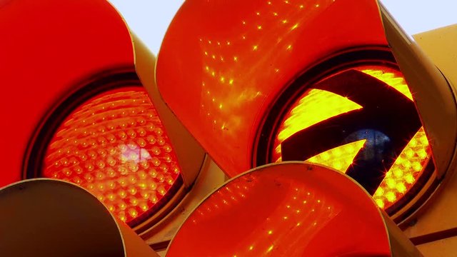 Close-up of a red traffic light with the red light going out after a while and a yellow turn right arrow flashing.