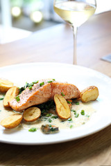 Salmon fillet with baked potatoes on a cream sauce with chives