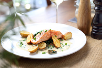 Grilling salmon fillet with baked potatoes on a cream sauce with chives