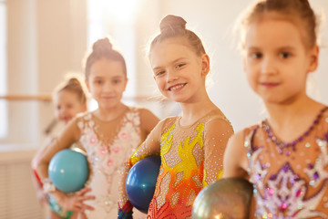 Group of little gymnasts standing in row and looking at camera