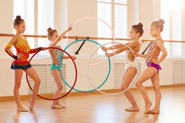 Team of little girls practicing rhythmic gymnastics with hoops, copy space