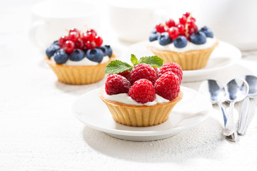mini tarts with cream and berries on white table