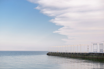 White sea pier and sky with clouds
