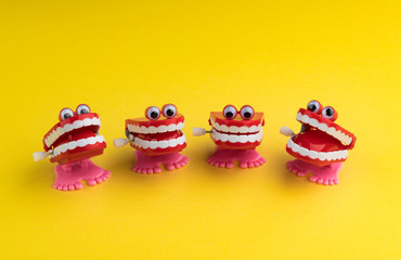 Four Clockwork Mouths Laughing and Staring on Yellow Background