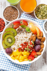 oatmeal porridge with fresh fruit and superfoods for healthy breakfast, top view, closeup