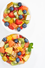 two bowls of fruit salad on white table, closeup top view