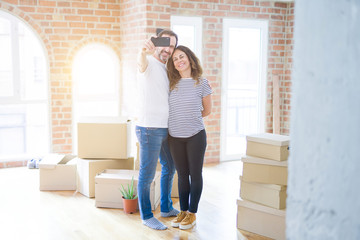 Middle age senior romantic couple taking a selfie picture with smartphone smiling happy for moving to a new house, making apartment memories