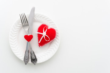 Romantic dinner concept. Ceramic plate with cutlery and felt hearts. Top view with copy space for banner design
