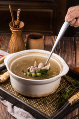 Stewed pig intestines with olives soup in a white ceramic pot