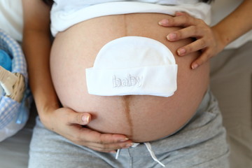 cute baby hat put on mother tummy pregnant awaiting for newborn