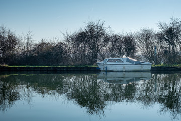 Boat on clear reflective canal on spring morning