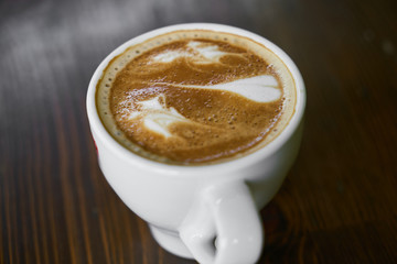 Cup of hot coffee latte on a wooden table