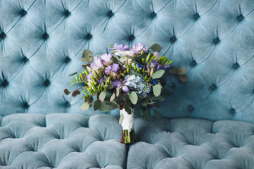 A beautiful wedding bouquet with wildflowers and roses lies against the backdrop of a blue sofa. Wedding photography, copy space, poster.