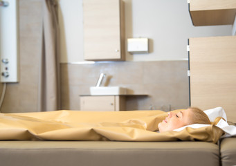 young beautiful woman are doing a fango therapie in a wellness area. friends are on the side of the water bed