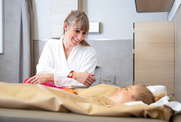 young beautiful woman are doing a fango therapie in a wellness area. friends are on the side of the water bed