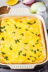 Onion pie with cheese and herbs in black baking dish.