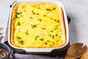Quiche with cheese and greens in a black baking dish.