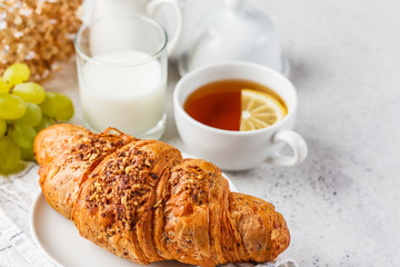 Croissant and tea for breakfast on white background, copy space.