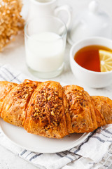 Croissant and tea for breakfast on white background.