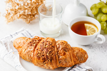 Croissant and tea for breakfast on white background.