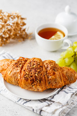 Croissant and tea for breakfast on white background.