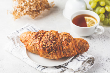 Croissant and tea for breakfast on white background.