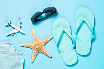 Blue flip flops, sunglasses and starfish on blue background.