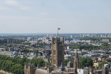 The westminster palace, parliament in London under construction with the union jack and a cityscape in the background.