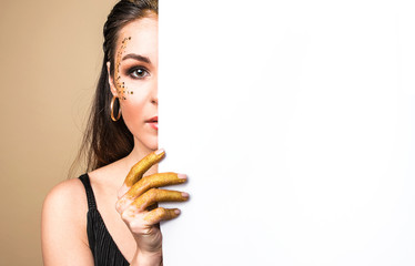 Beautiful woman with a glitter hands holds blank poster.