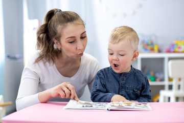 Speech therapist teaching letter pronunciation to kid boy in classroom