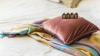 A decorative cozy pillow and the inscription HOME. In the home with a blanket. HOME concept