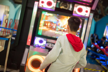 A boy dancing with game arcade machine in selective focus.