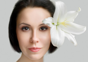 Fototapeta premium large portrait of a girl. european girl with lily. beautiful healthy face skin