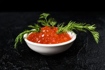 Red Caviar in bowl over black background