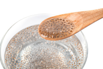 Spoon with water and chia seeds over glass on white background